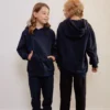 Twee kinderen dragen een marineblauwe fidget hoodie; ontspannen houding en zachte stof laten zien hoe comfortabel de fidget hoodie kind aanvoelt.