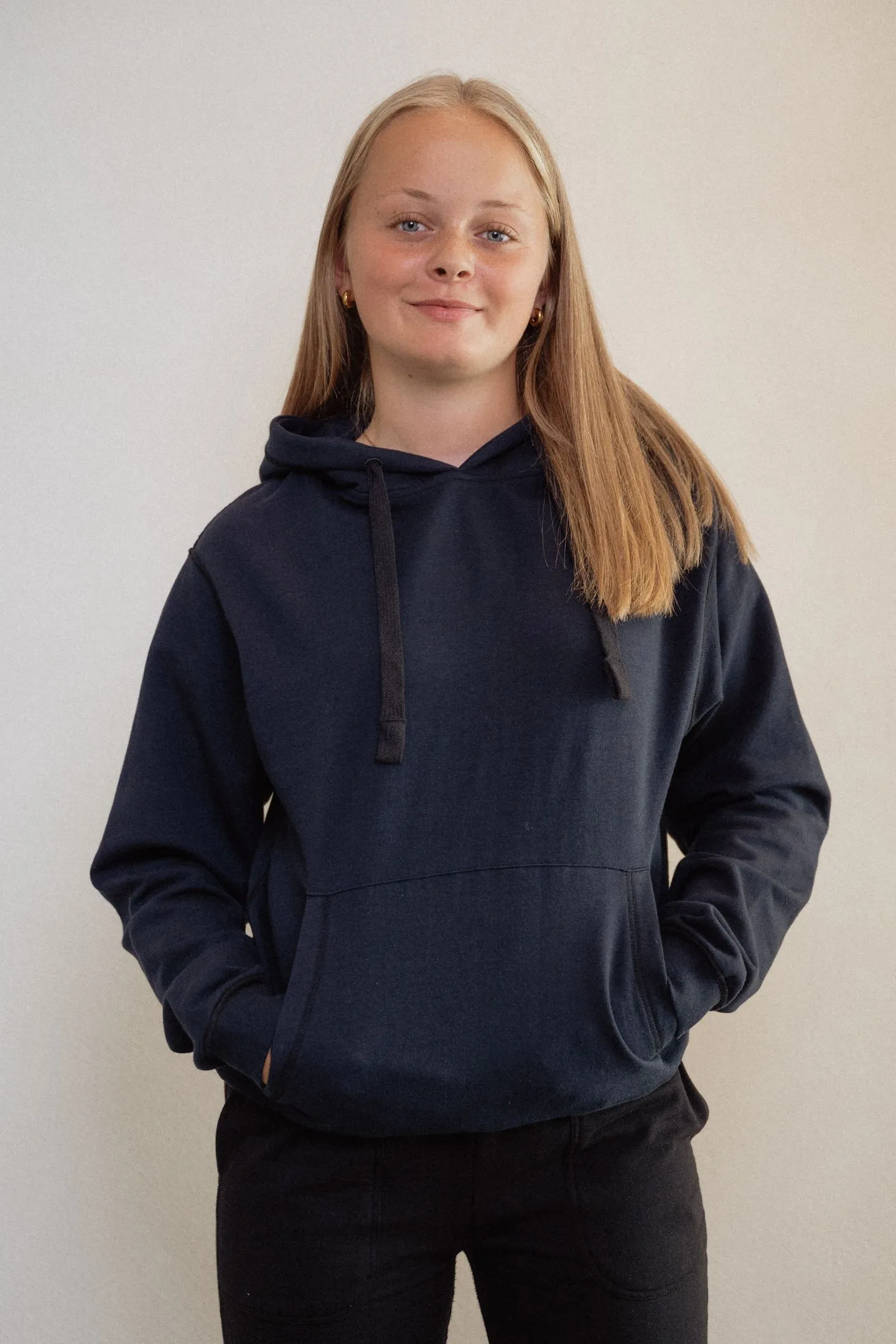 Tiener draagt een zachte, prikkelarme fidget hoodie in marineblauw; ontspannen uitstraling en comfortabele pasvorm.