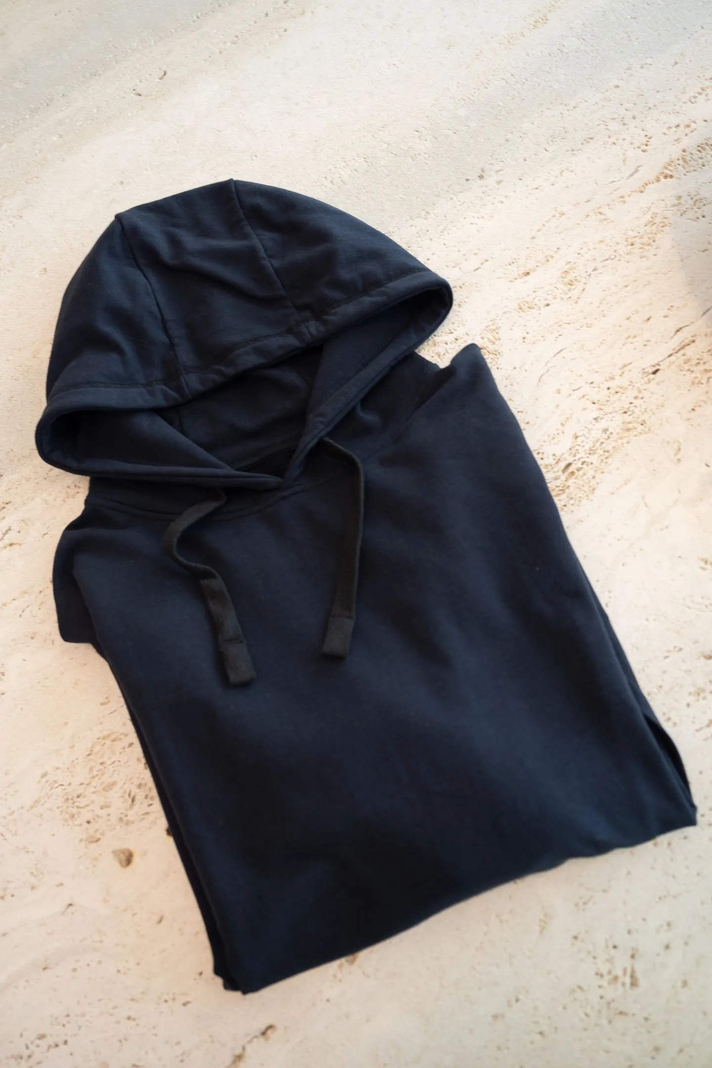 Marineblauwe fidget hoodie voor kinderen, netjes opgevouwen om de zachte stof en eenvoudige afwerking te tonen.