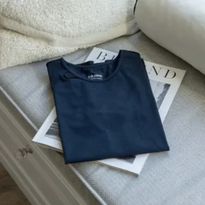 Opgevouwen blauw T-shirt op een bed, zacht en sensorisch vriendelijk.